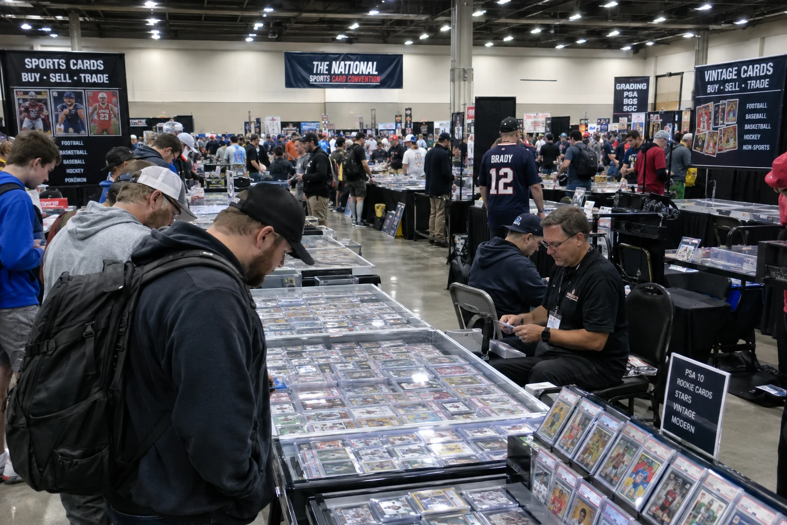 A busy card show floor with dealer tables, display cases of graded sports cards, and collectors walking the aisles