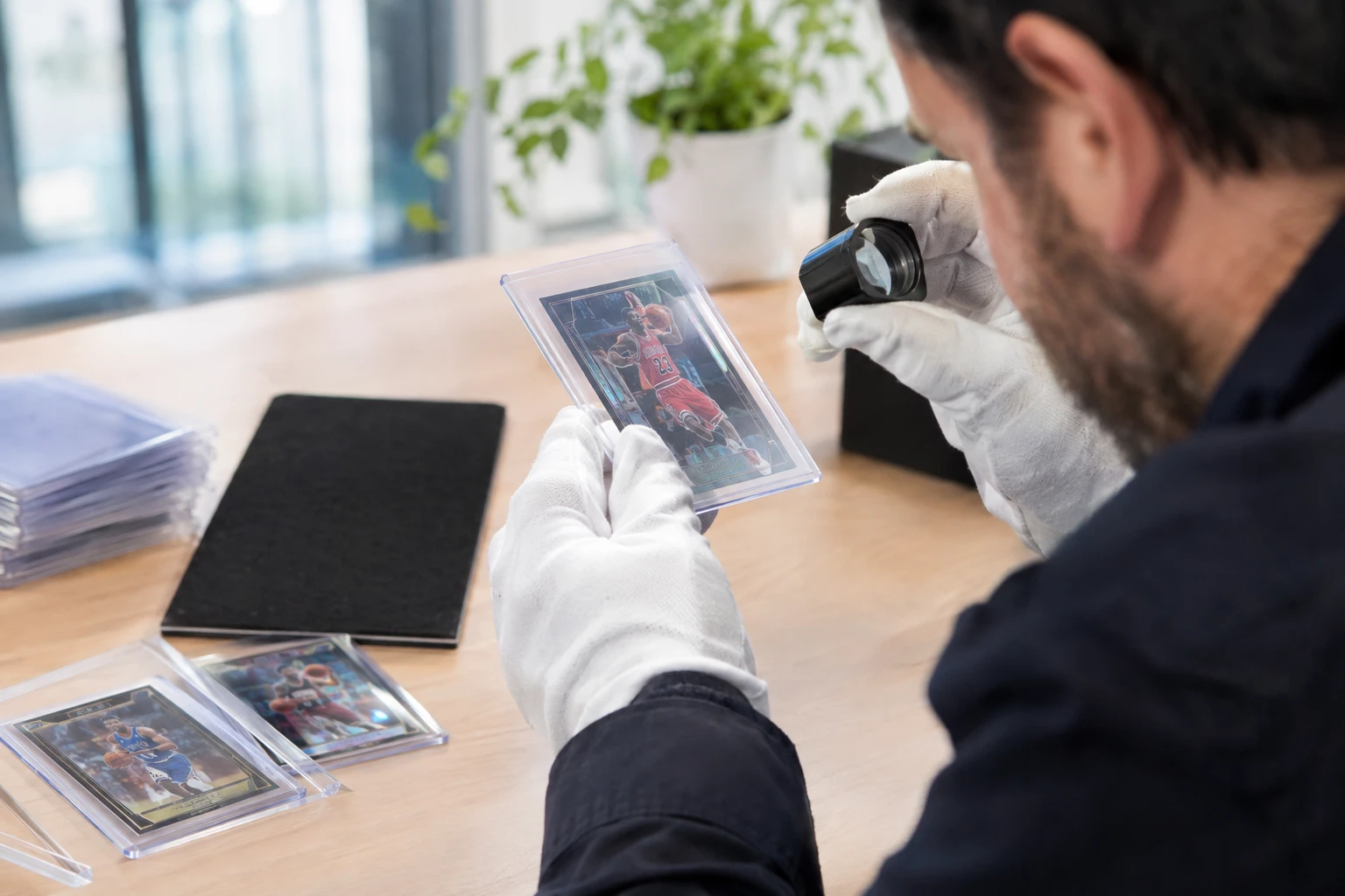 A trading card being inspected with a jeweler's loupe under a bright desk lamp
